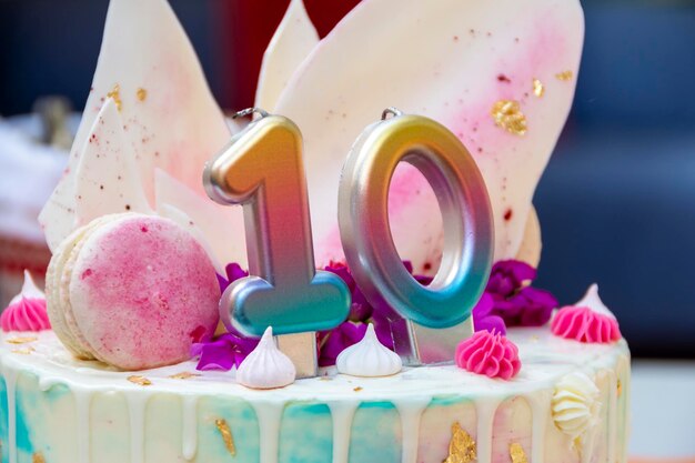 Foto torta rosa bianca e blu con il numero 10 sul tavolo sullo sfondo di pacchetti con regali festa di compleanno per bambini