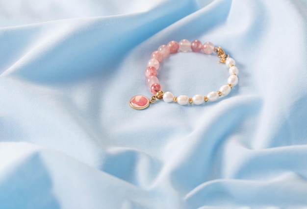 pink and white bracelet made of natural stones on blue silk fabric