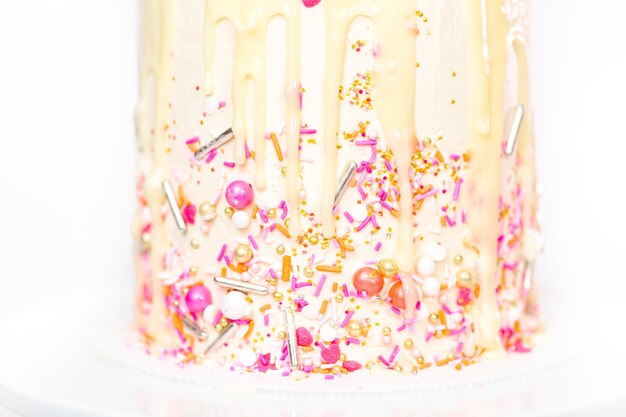 Photo pink and white buttercream cream cake with pink sprinkles and white chocolate ganache drip.