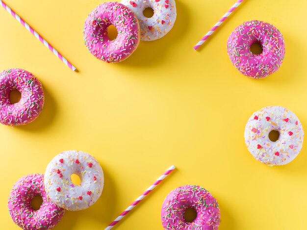 Pink and white donuts with celebration item on yellow