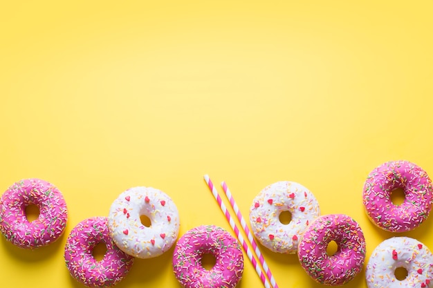 Pink and white donuts with celebration item on yellow