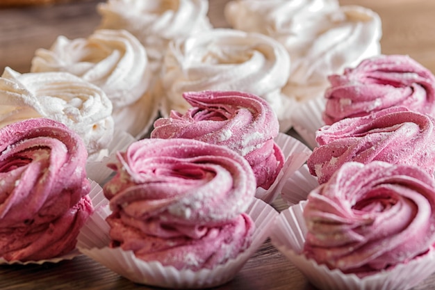 Caramelle gommosa e molle casalinghe rosa e bianche su un fondo di legno grigio.