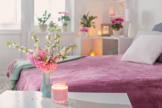 Pink and white interior of bedroom with spring flowers