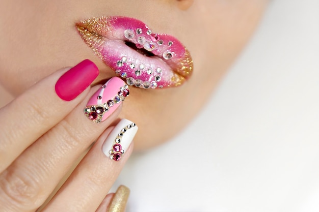 Pink and white lip makeup and manicure with rhinestones