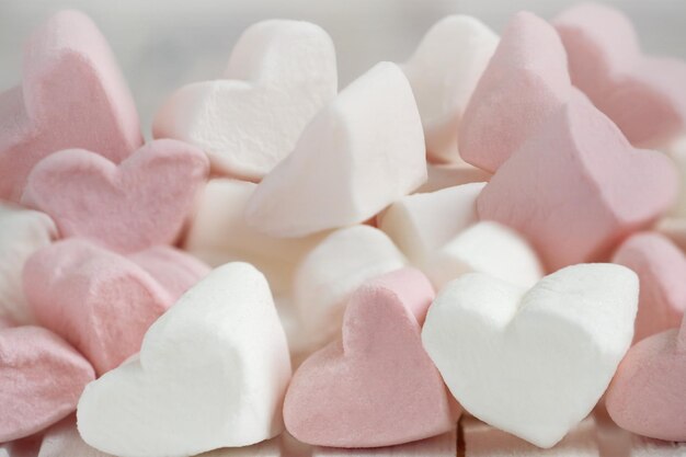 Photo pink and white marshmallows in the shape of hearts on pink abstract background valentines concept