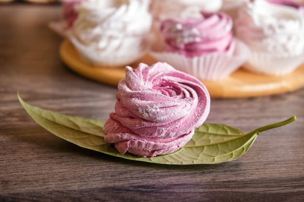  pink and white marshmallows (zephyr) on a round wooden board 