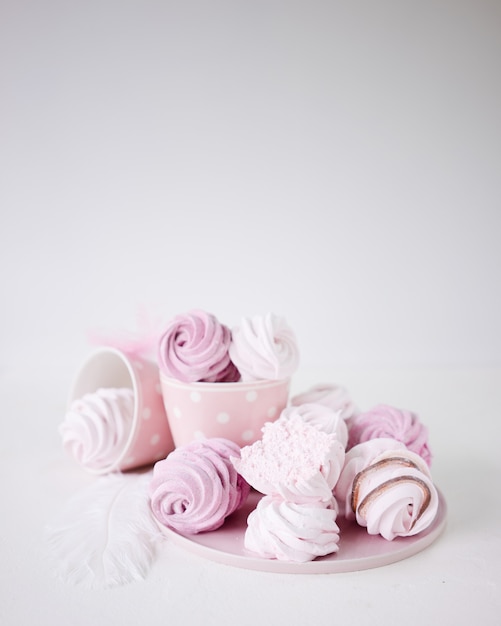 Pink and white meringues on white background.