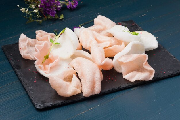 Pink and white shrimp chips on a black stone