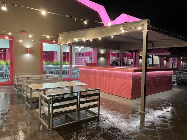Pink and white terrace of a street cafe with cozy lighting at night
