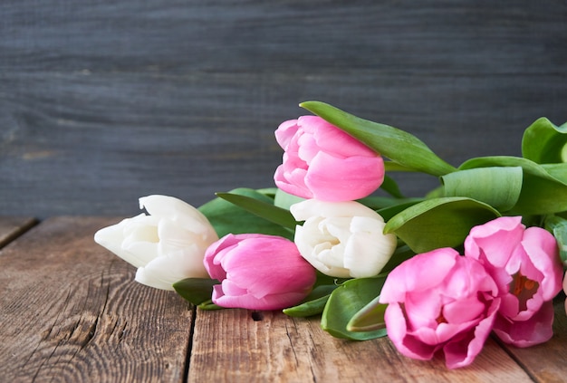 Pink and white tulips on a wooden table