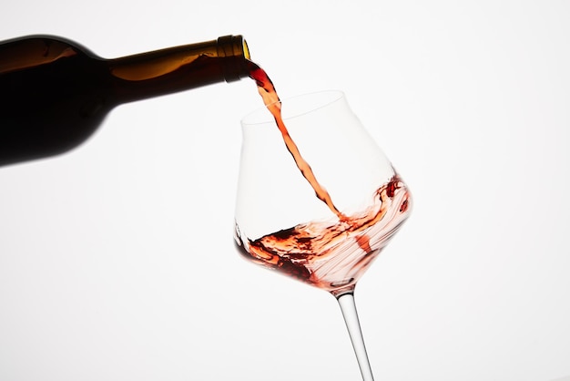 Pink wine pouring into tilted wineglass from amber glass bottle Red alcoholic drink served aperitif