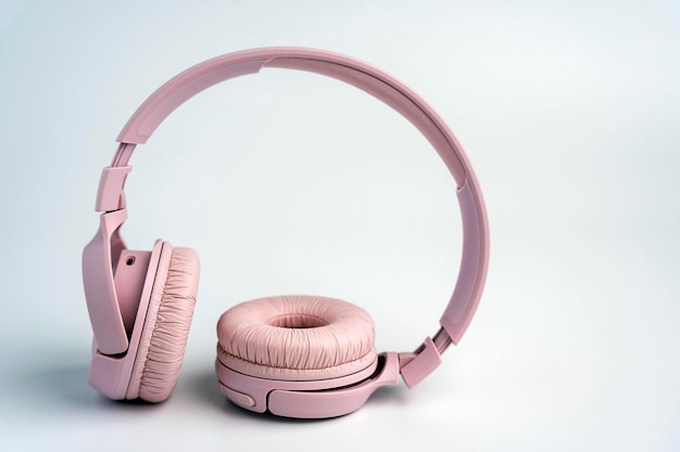 Pink wireless headphones on a white background Music time space for text Ready to listen to music