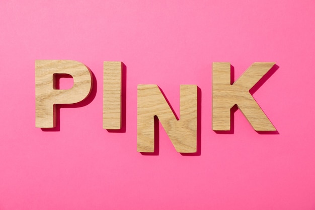 Pink word made from wooden letters on pink background