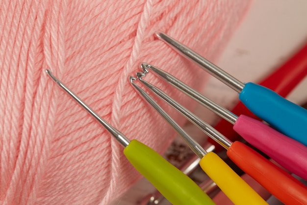 Фото Розовая пряжа и красочные крючки для вязания крупным планом.