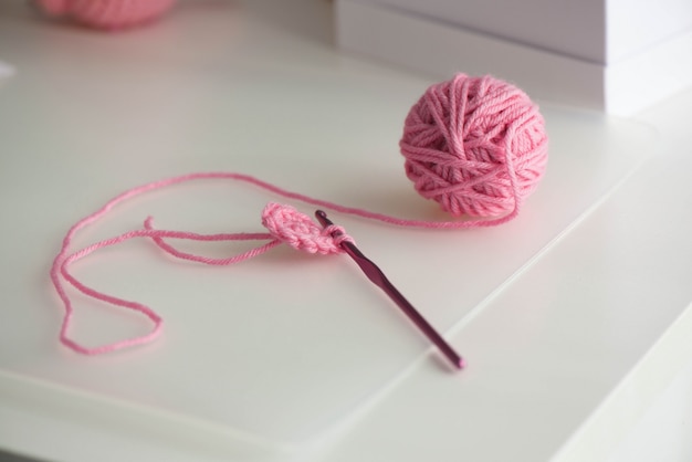 Pink yarn ball with woolen thread on white