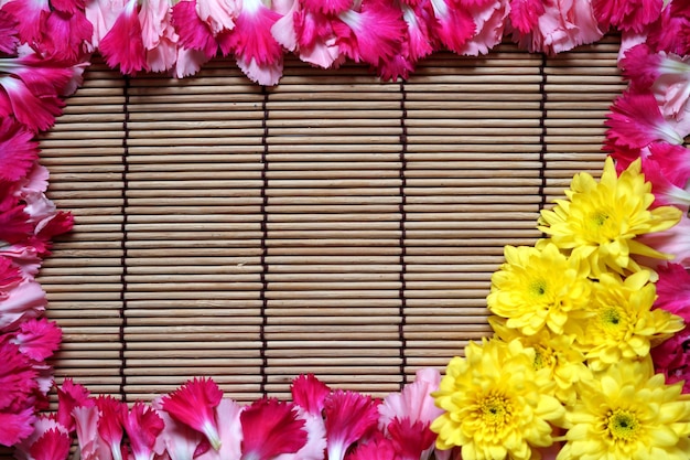 Pink and yellow flowers on wooden frame background