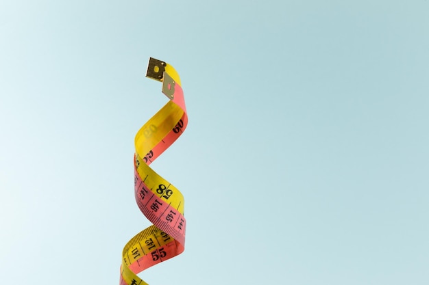 Pink and yellow measuring tape on cyan background