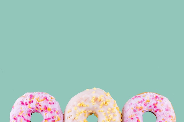 Pink and yellow spricled donuts on a green background Space for text highquality photos