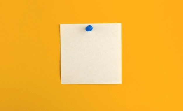 写真 メッセージと仕事の手紙のために、孤立した黄色の背景に正方形の紙のピン留めされたメモ帳シート