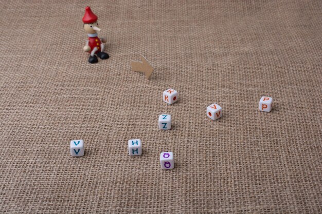 Photo pinocchio sitting on canvas beside letter cubes