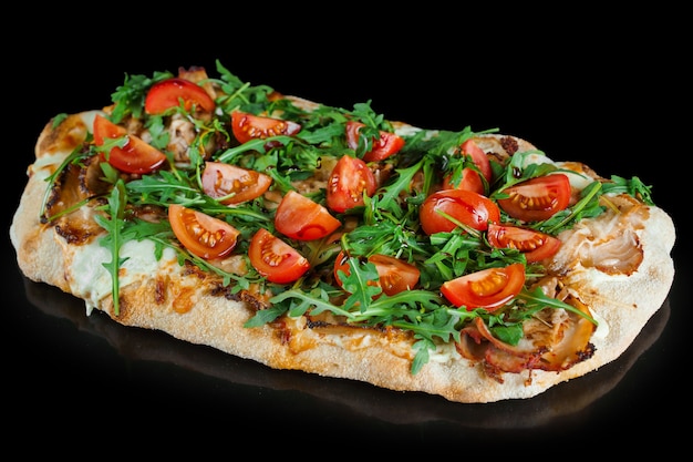 Pinsa romana gourmet italian cuisine on black background. Scrocchiarella. Pinsa with meat, arugula, tomatoes, cheese.