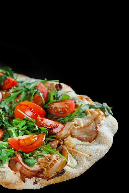 Pinsa romana gourmet italian cuisine on black background. Scrocchiarella. Pinsa with meat, arugula, tomatoes, cheese.