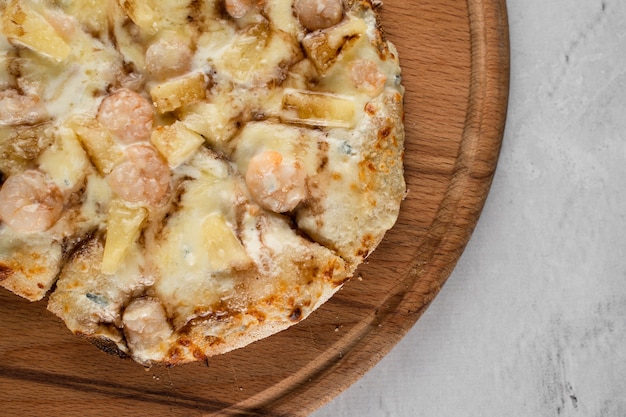 Pinsa romana with shrimps and pineapple on wooden plate on white background. Seafood scrocchiarella.