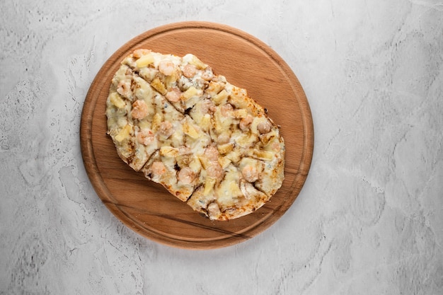 Pinsa romana con gamberi e ananas su piatto di legno su sfondo bianco. scrocchiarella di mare.