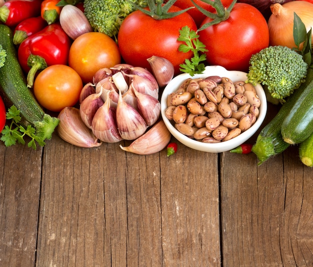 Pinto beans in a bowl and vegetables on wood close up with a copy space