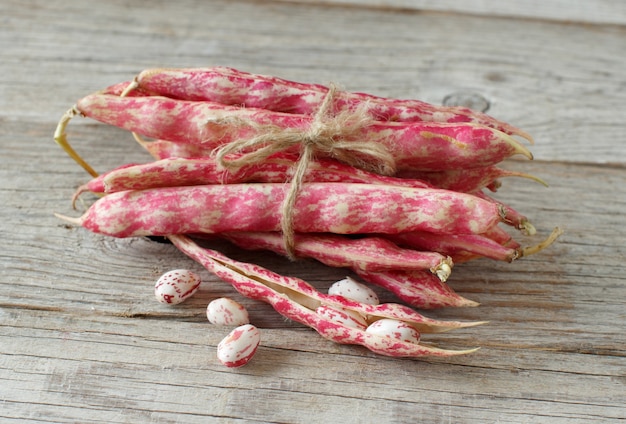 Pinto beans with pods on a wooden table close up