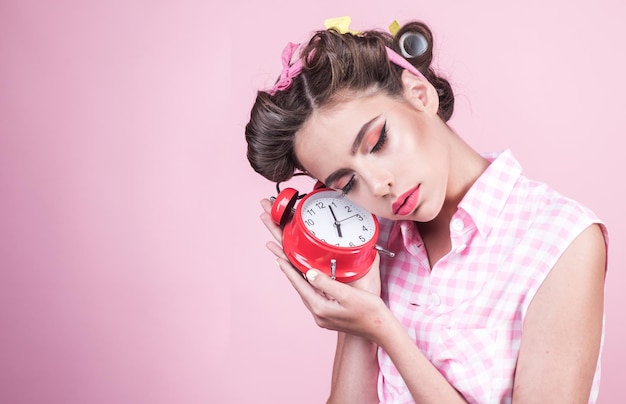 Foto pinup ragazza con capelli alla moda pin up donna con trucco alla moda buongiorno gestione del tempo donna retrò con sveglia tempo sonnolento ragazza stanca in stile vintage copia spazio tempo per rilassarsi