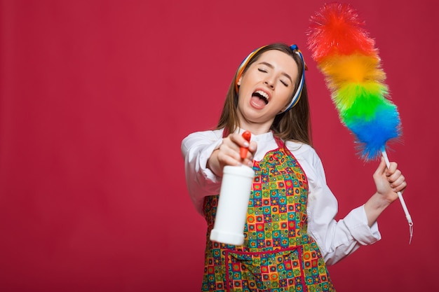 Pinup vrouw houdt soepfles stofdoek pinup vrouw met blij gezicht op roze achtergrond