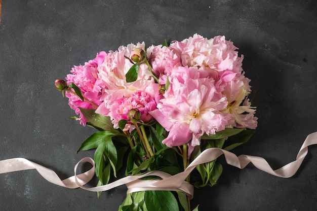 Pioenen plat leggen. Mooie pioenroos bloemen op donkere muur.