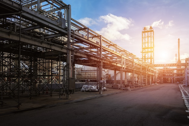 Трубопровод и стойка нефтеперерабатывающего завода с закатом фоне неба