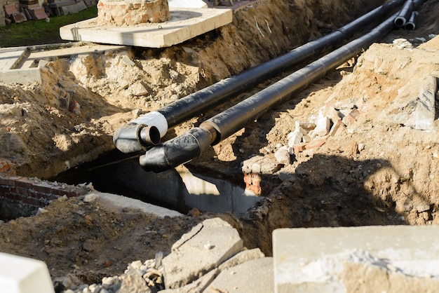 Photo pipeline repair, laying new pipes underground. selective focus on foreground of black pipes.