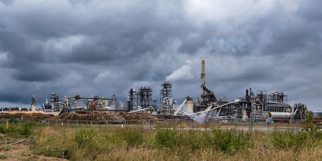 Foto tubi di segheria per impianti di lavorazione del legno contro un cielo grigio cupo concetto di inquinamento atmosferico panorama del paesaggio industriale rifiuti di inquinamento ambientale della centrale termica