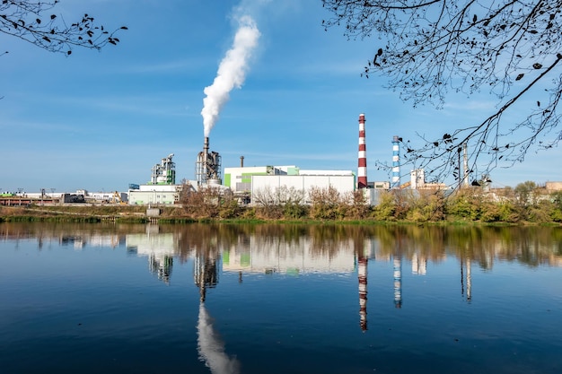 강 근처 목공 기업 공장 제재소의 파이프 대기 오염 개념 산업 경관 환경 오염 폐기물 화력 발전소
