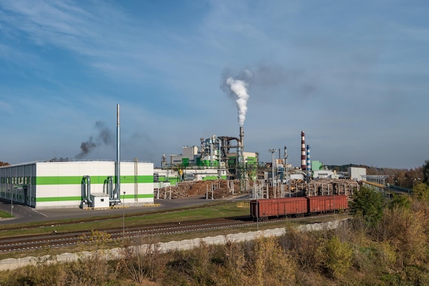 Pipes of woodworking enterprise plant sawmill near river air\
pollution concept industrial landscape environmental pollution\
waste of thermal power plant