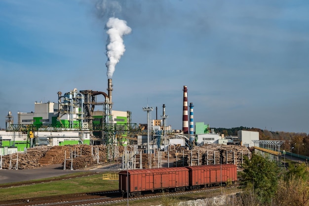 Tubi di segheria per impianti di lavorazione del legno vicino al fiume concetto di inquinamento atmosferico paesaggio industriale rifiuti di inquinamento ambientale della centrale termica