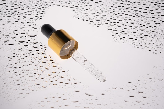 Photo a pipette of cosmetic gel on the background of drops