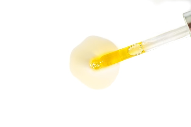 Pipetta di siero cosmetico o olio con goccia isolata su sfondo bianco vista dall'alto