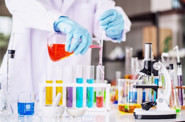 A pipette dropping sample into a test tube, abstract science background