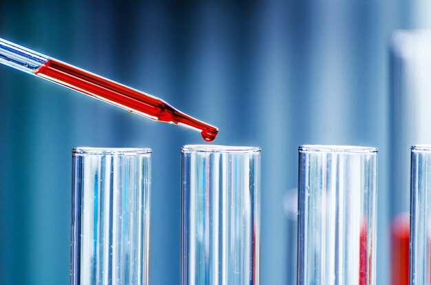 A pipette dropping sample into a test tube,abstract science background