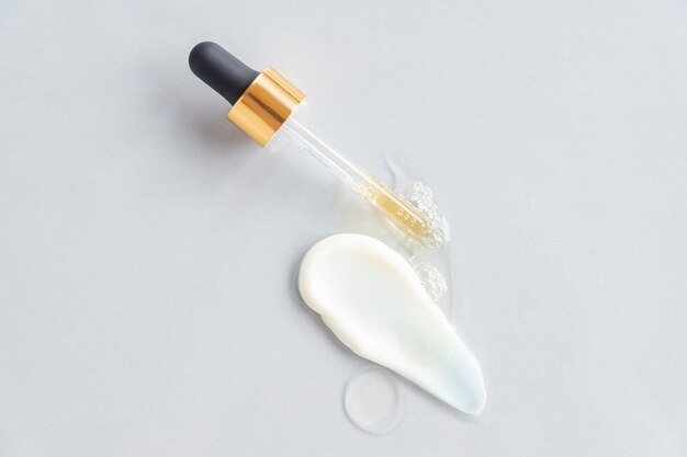 Pipette and drops and smears of cosmetics Liquid gel or a drop of serum with face cream smear Netural organic cosmetic