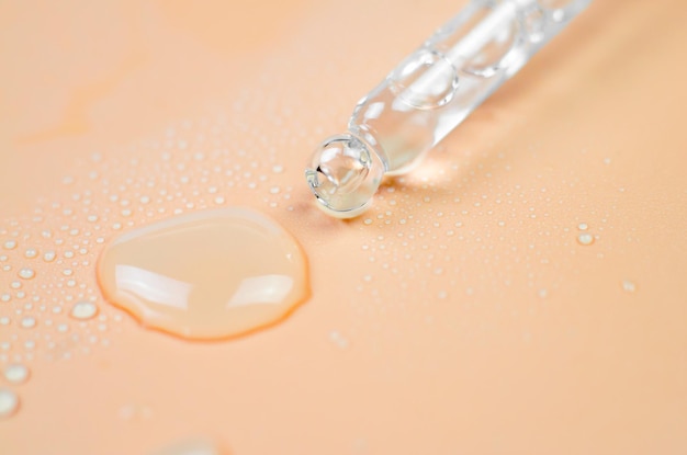 Pipette and liquid closeup on a peachcolored background selective focus Collagen hyaluronic acid for skin care Laboratory research and development of body care cosmetic