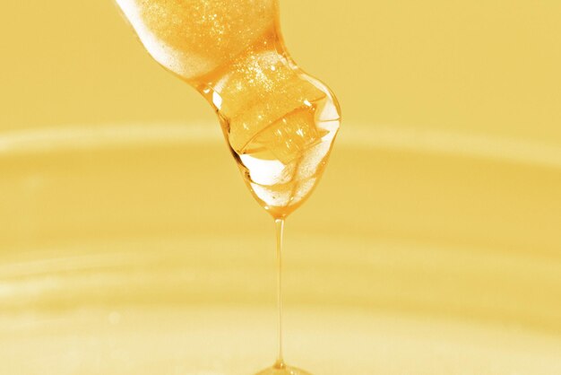 滴る黄色の液体または液体の金のクローズ アップとピペット金色の背景に実験室化学医学化粧品研究輝き