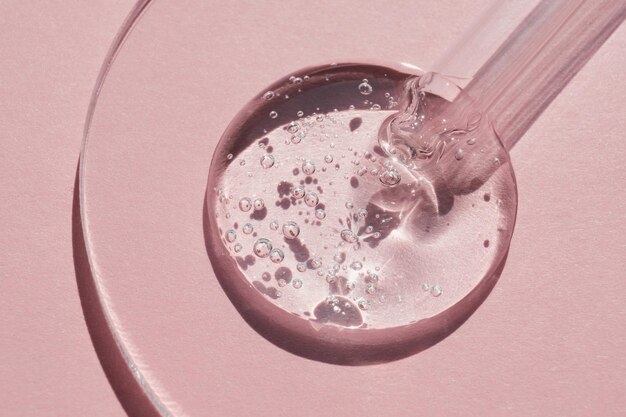 Pipette with sample of gels cosmetic product in petri dish on pink background hard shadows