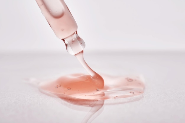 Pipette with a viscous pink cosmetic closeup