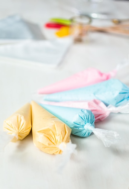 Piping bags with pastel color royal icing to decorate Easter sugar cookies.