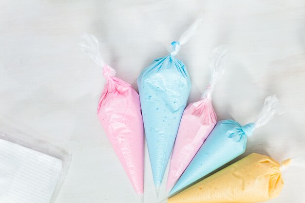 Piping bags with pastel color royal icing to decorate Easter sugar cookies.